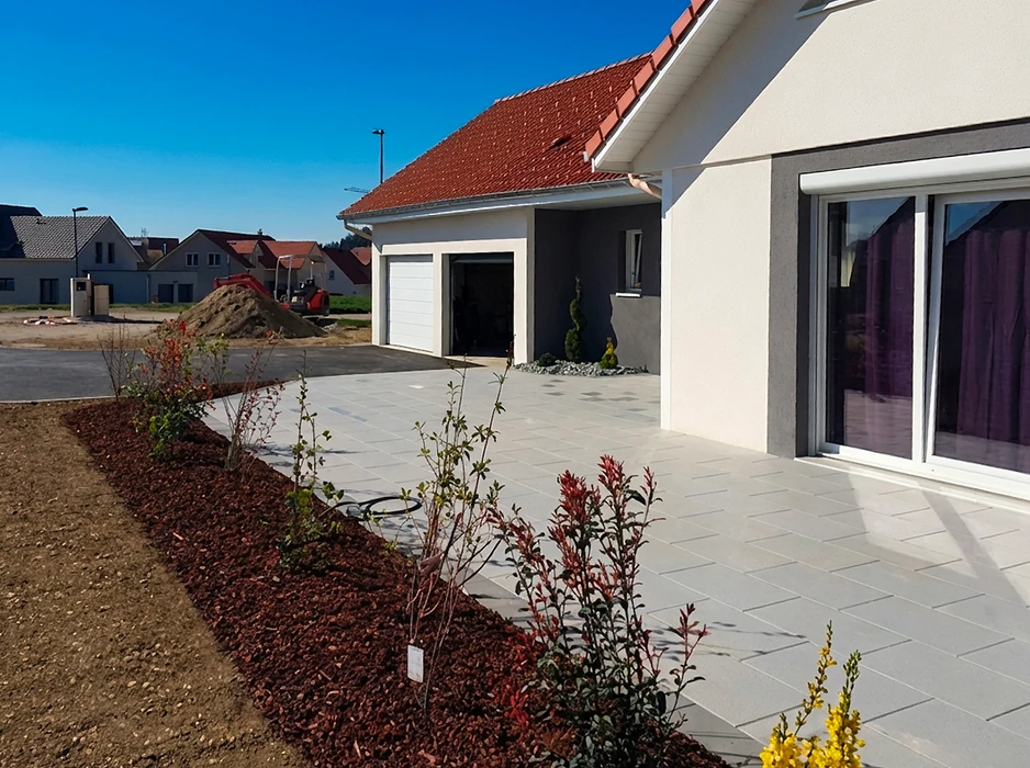 Terrasse extérieure d'une maison neuve, dallage en béton gris clair, format rectangulaire, pose en décalé